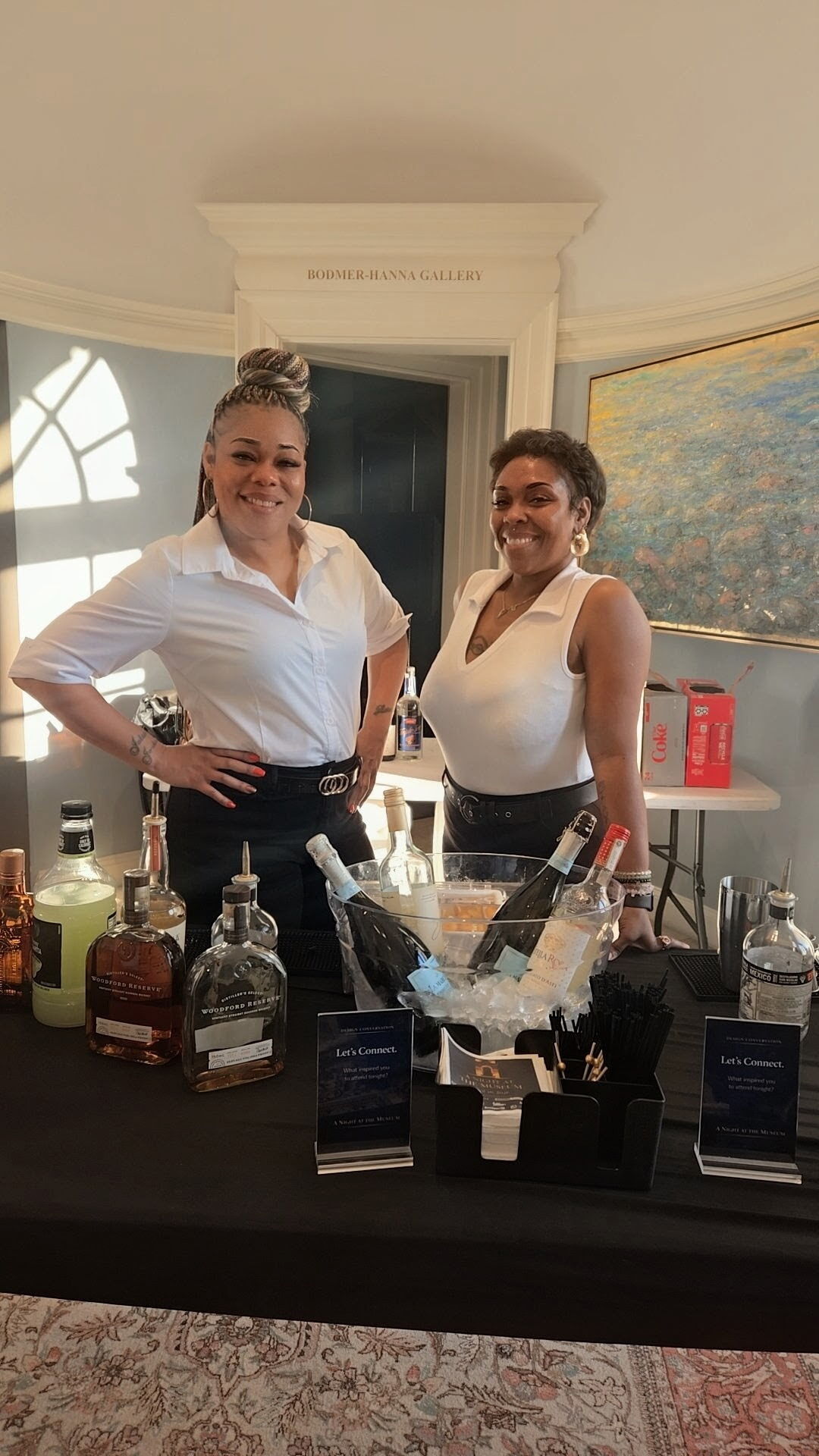 Two bartenders preparing bottles and tools for a mobile event bar